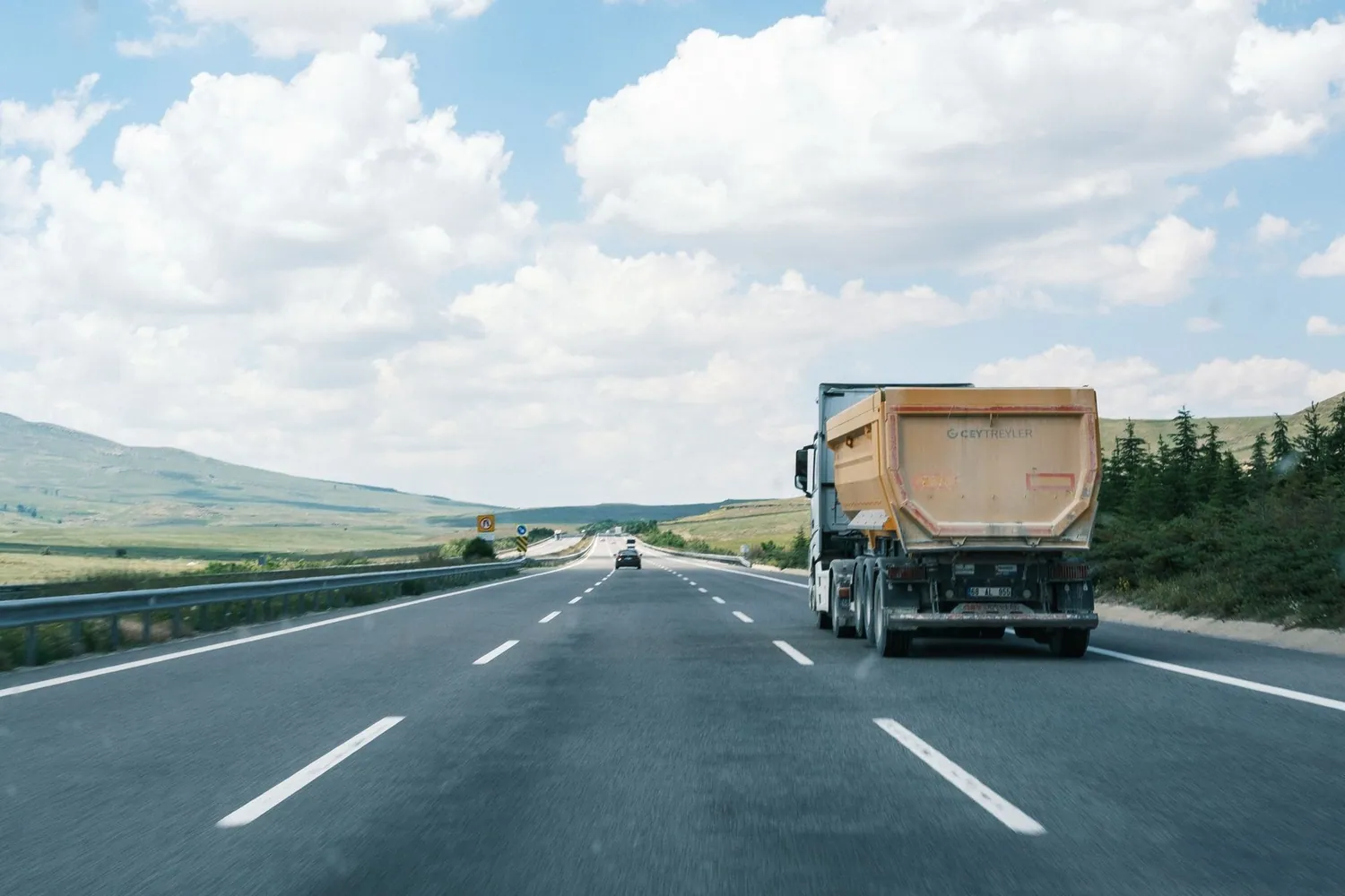 Cargo truck travelling along an open highway beneath a bright blue sky